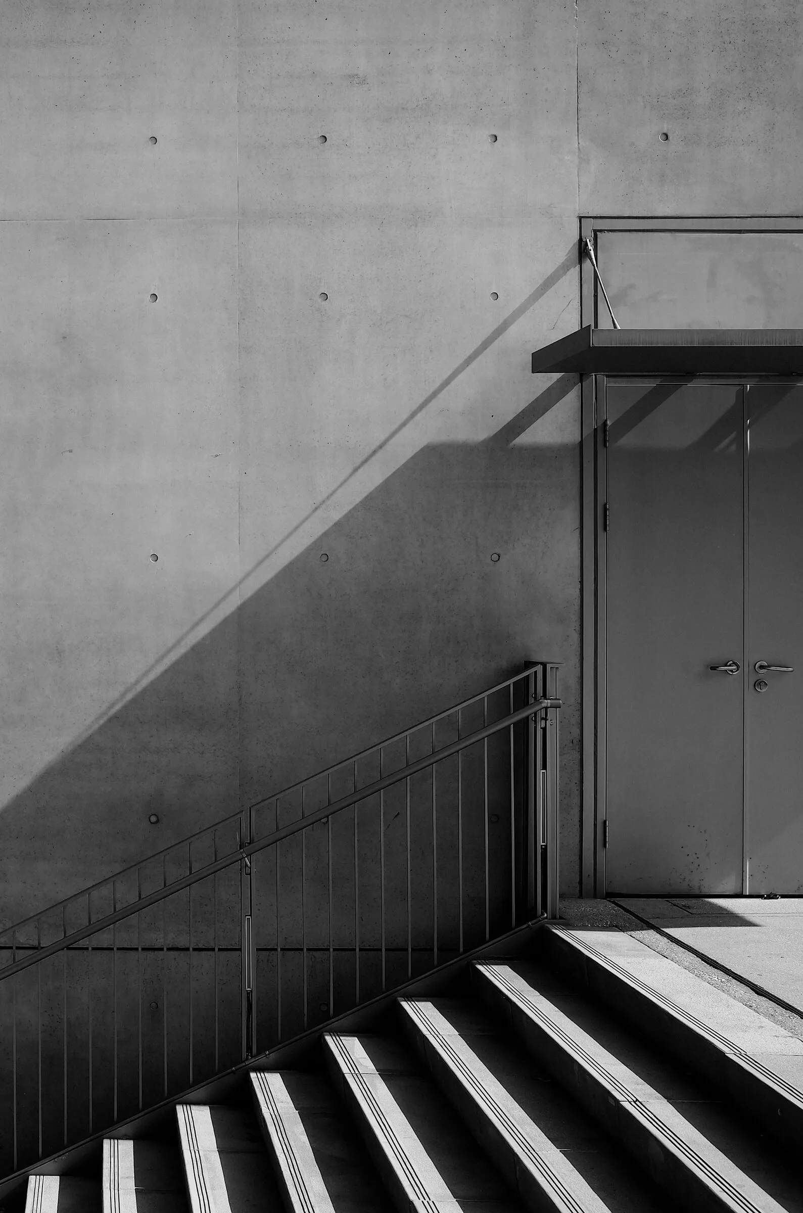 Concrete wall and stair with a long diagonal shadow, in black and white