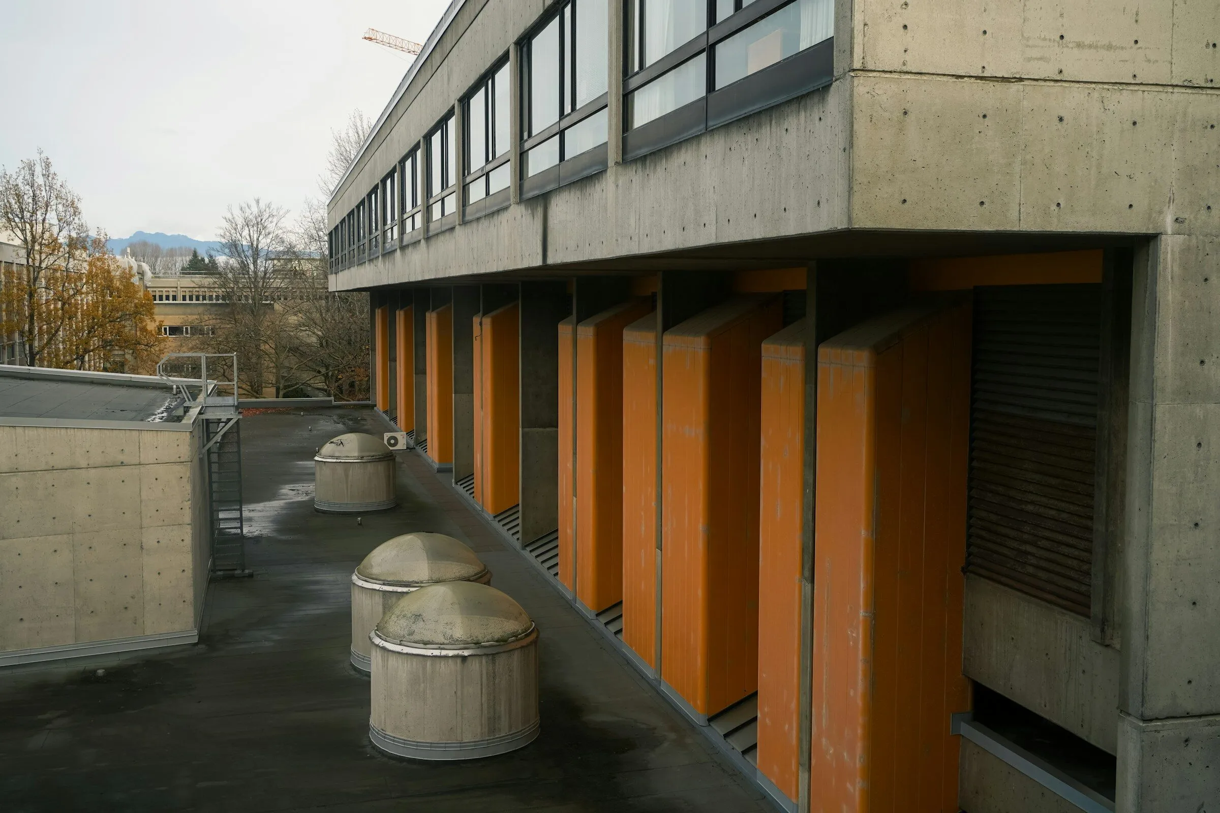 Exposed concrete building with a row of orange vertical fins along its facade