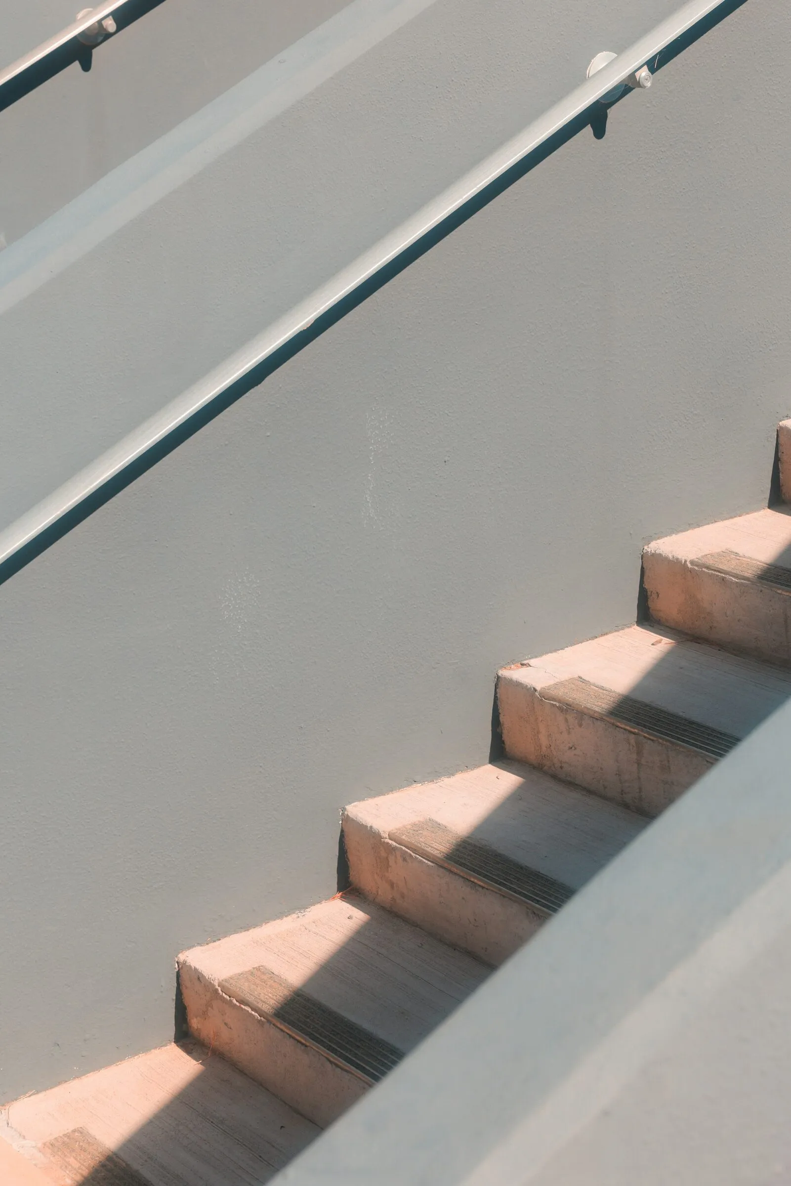 Plastered stair with a slim handrail in afternoon light
